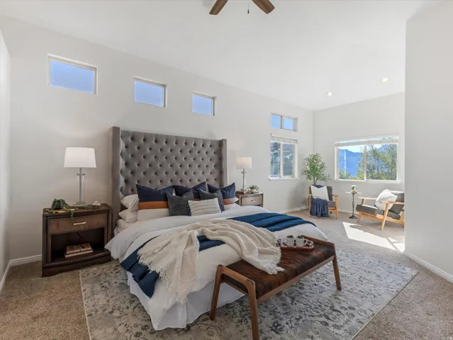 Vaulted ceiling, recessed lighting, ceiling fan, multiple windows, and carpet flooring