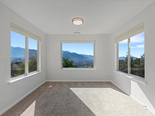 Mountain scenery visible through multiple windows, complemented by a flush-mount ceiling light fixture and carpeted flooring