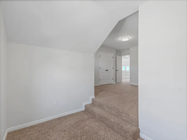 Neutral-toned carpeting throughout, crisp white walls, and a modern flush-mount ceiling light