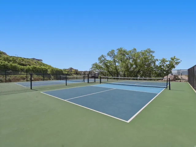 Two hard surface courts with painted lines and nets, surrounded by chain link fencing