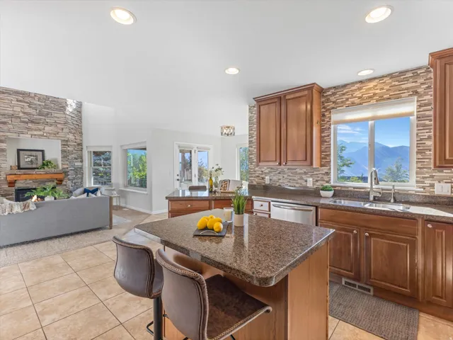 Open concept living space featuring a stone-clad fireplace, vaulted ceiling, and recessed lighting