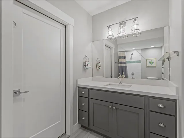 Bathroom featuring a single vanity with gray cabinetry, a white countertop, and an undermount sink