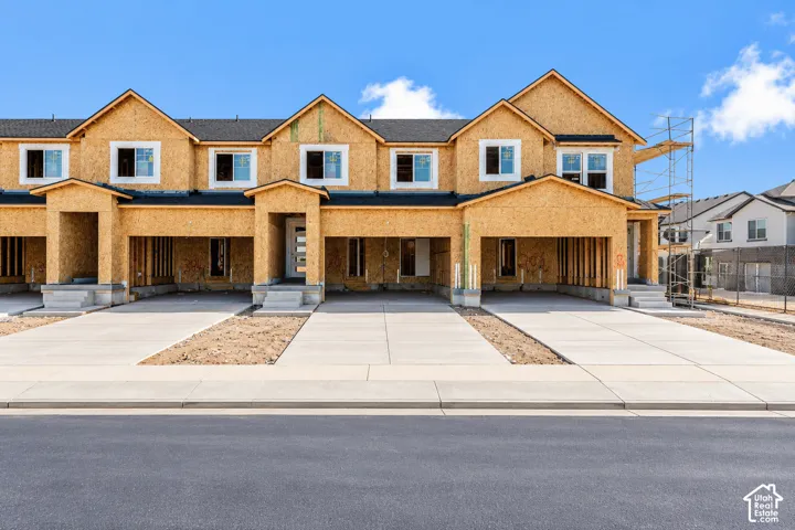 New construction townhouse complex featuring multi-gabled rooflines, dark asphalt shingle roofing, dual-pane white-frame windows, and private concrete driveways