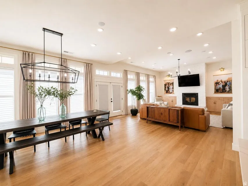 Open-concept living area with wood-finish flooring, recessed lighting, and a white tile fireplace surround