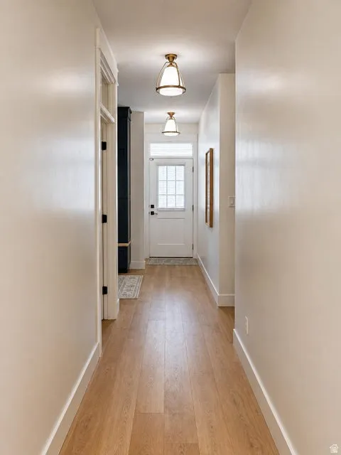 Hallway with wood-finish flooring, white walls, and two semi-flush mount light fixtures