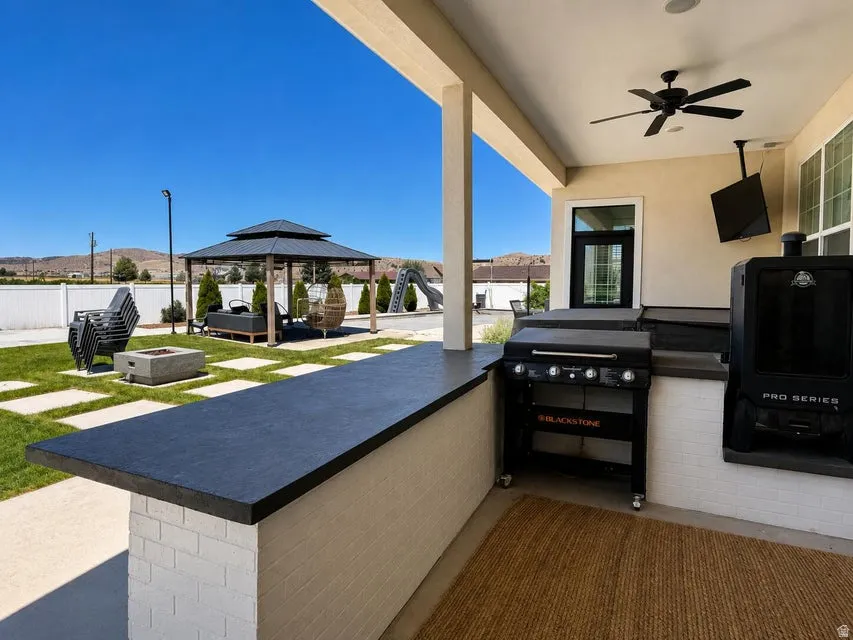 Covered patio with an outdoor kitchen, ceiling fan, and built-in counter