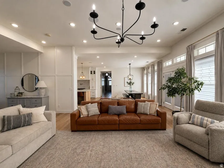Open-concept living space featuring wood-finish flooring, recessed lighting, and a prominent chandelier