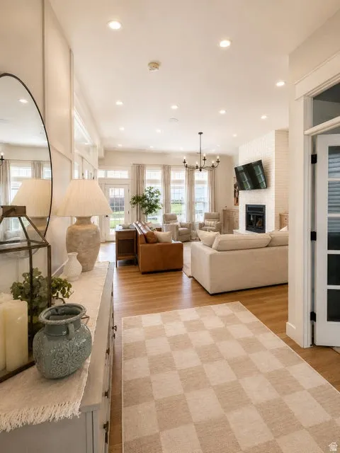 Expansive living area with wood-finish flooring, recessed lighting, and a fireplace with a tiled surround