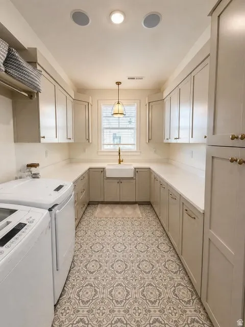 U-shaped cabinetry with ample counter space, integrated farmhouse sink with a brass faucet, and patterned tile flooring