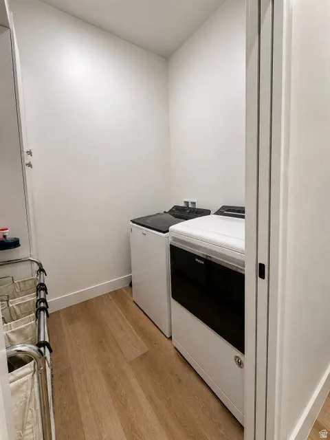Laundry area featuring wood-finish flooring, white walls, and built-in appliances