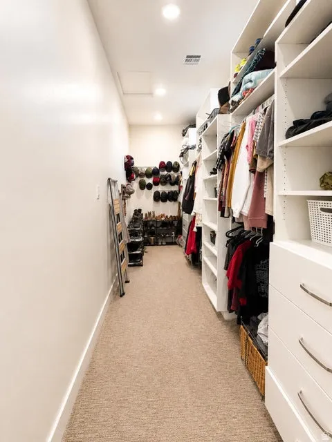 Walk-in closet featuring recessed lighting, a neutral carpeted floor, and extensive built-in shelving with integrated drawers