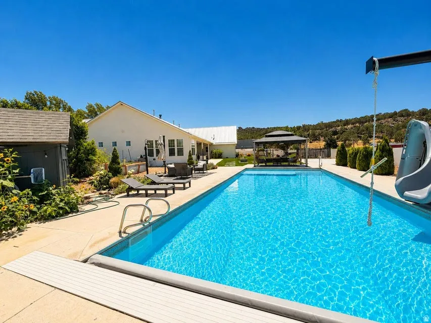Resort-style swimming pool with crystal-clear water and integrated sun shelf, surrounded by expansive concrete decking