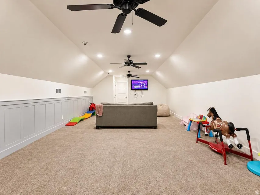 Carpeted room featuring multiple ceiling fans, recessed lighting, and wainscoting