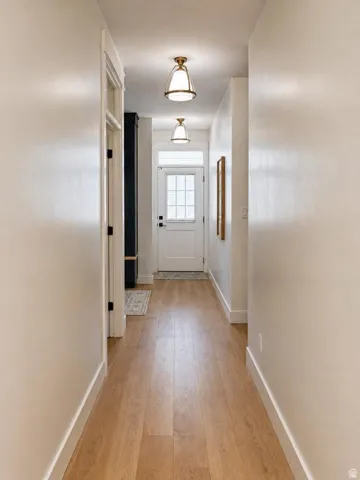 Hallway with wood-finish flooring, white walls, and two semi-flush mount light fixtures