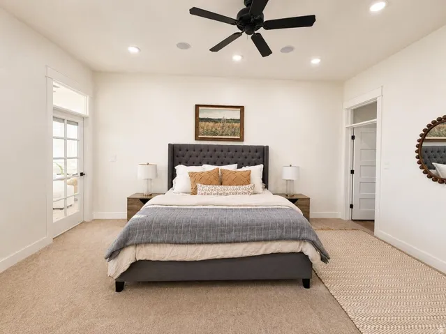 Plush carpet flooring, recessed ceiling lighting, a black ceiling fan, and French doors with transom windows