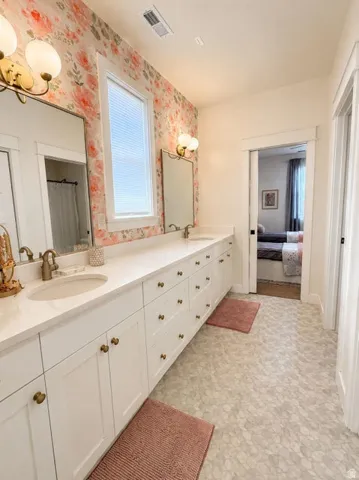 Dual vanity with white cabinetry and gold-toned hardware, featuring two undermount sinks and individual mirrors