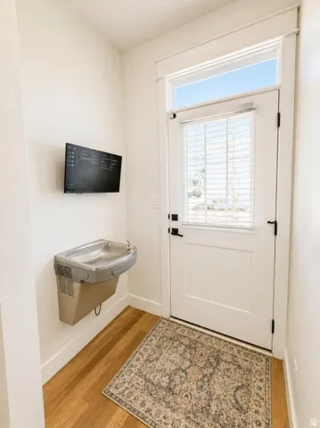 Entryway featuring wood-finish flooring, a white door with a transom window, a wall-mounted water fountain, and a wall-mounted display