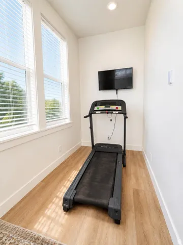 Bright room featuring large windows with blinds, wood-finish flooring, and recessed lighting