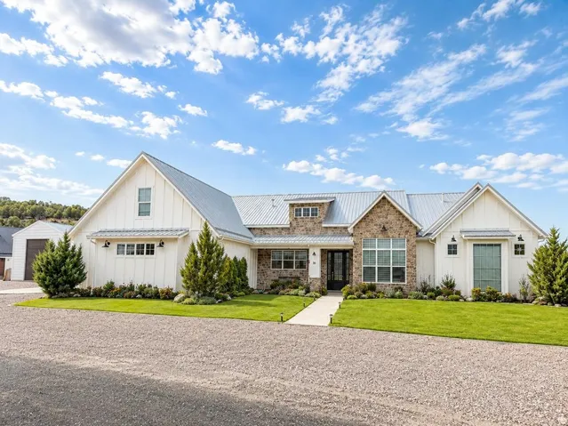 Modern farmhouse exterior featuring vertical white siding and stone accents