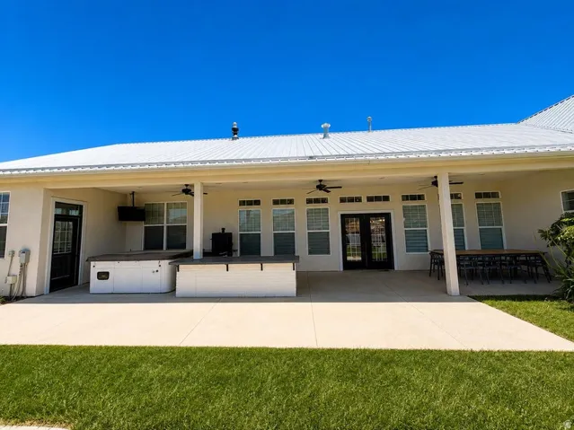 Expansive covered patio with a white metal roof, built-in hot tub, and an integrated outdoor kitchen