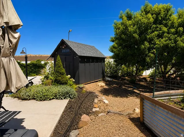 Backyard features a paved patio, gravel landscaping, a detached storage shed, and mature trees