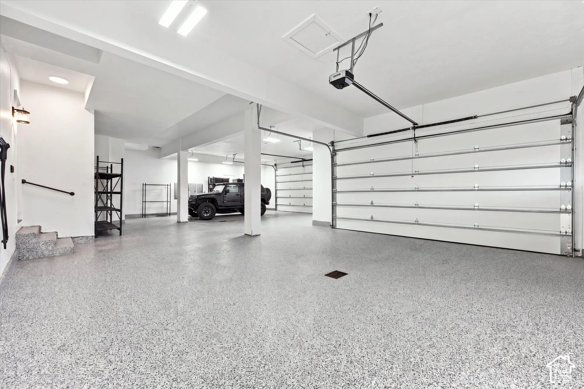 Spacious 4 bay garage featuring a durable epoxy floor, multiple overhead doors, recessed lighting, and structural support beams