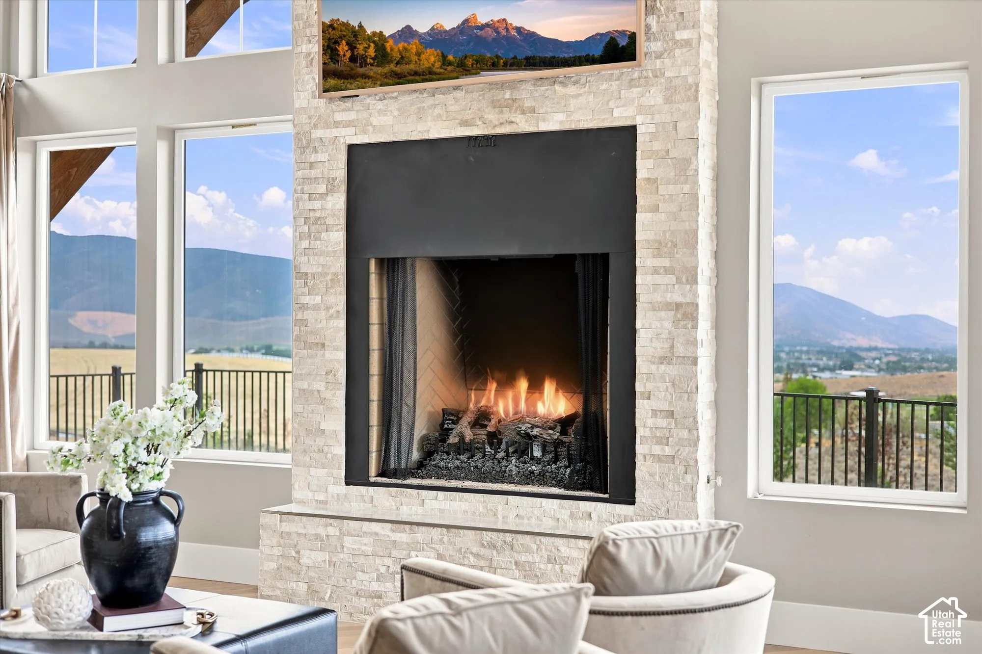 Stacked stone fireplace with a black firebox, surrounded by multiple large windows and a white trim