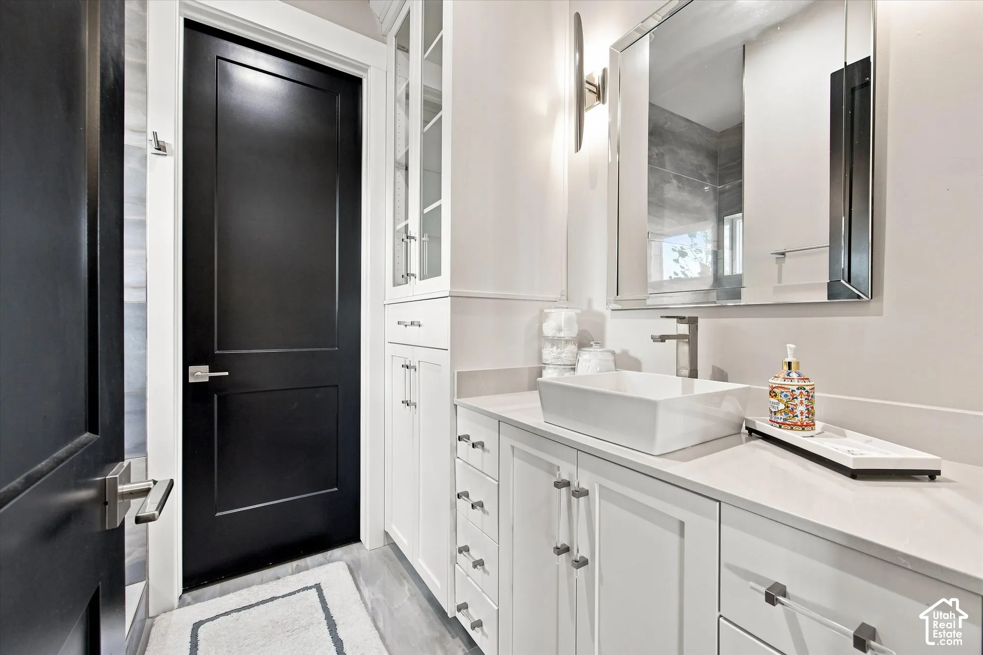 White vanity with a rectangular vessel sink, brushed nickel faucet, and a wall-mounted mirror