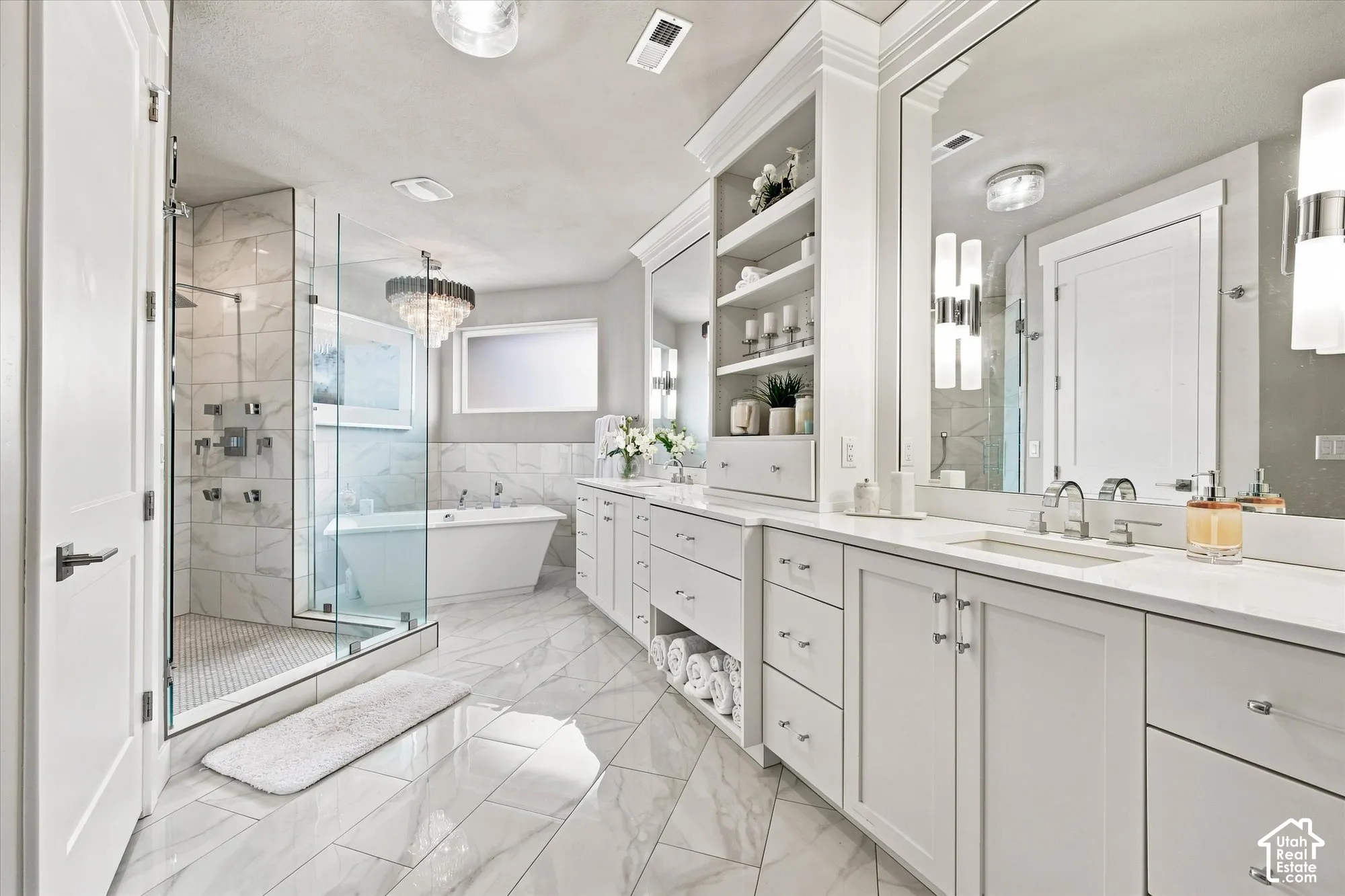 Primary En-suite bathroom featuring a frameless glass shower enclosure, freestanding soaking tub, dual vanity with white cabinetry, and large format marble-look tile flooring