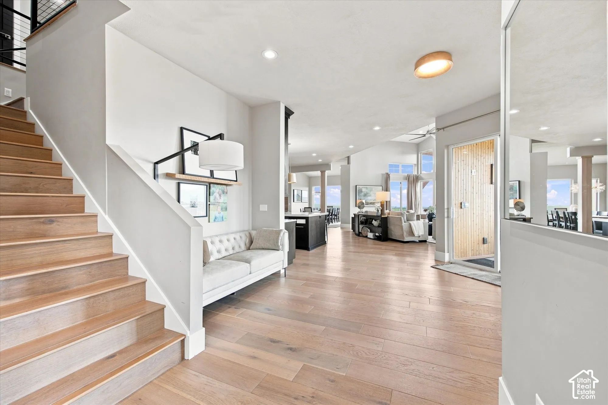 Hardwood flooring throughout, a wood-finish entry door, and a built-in staircase with a metal railing