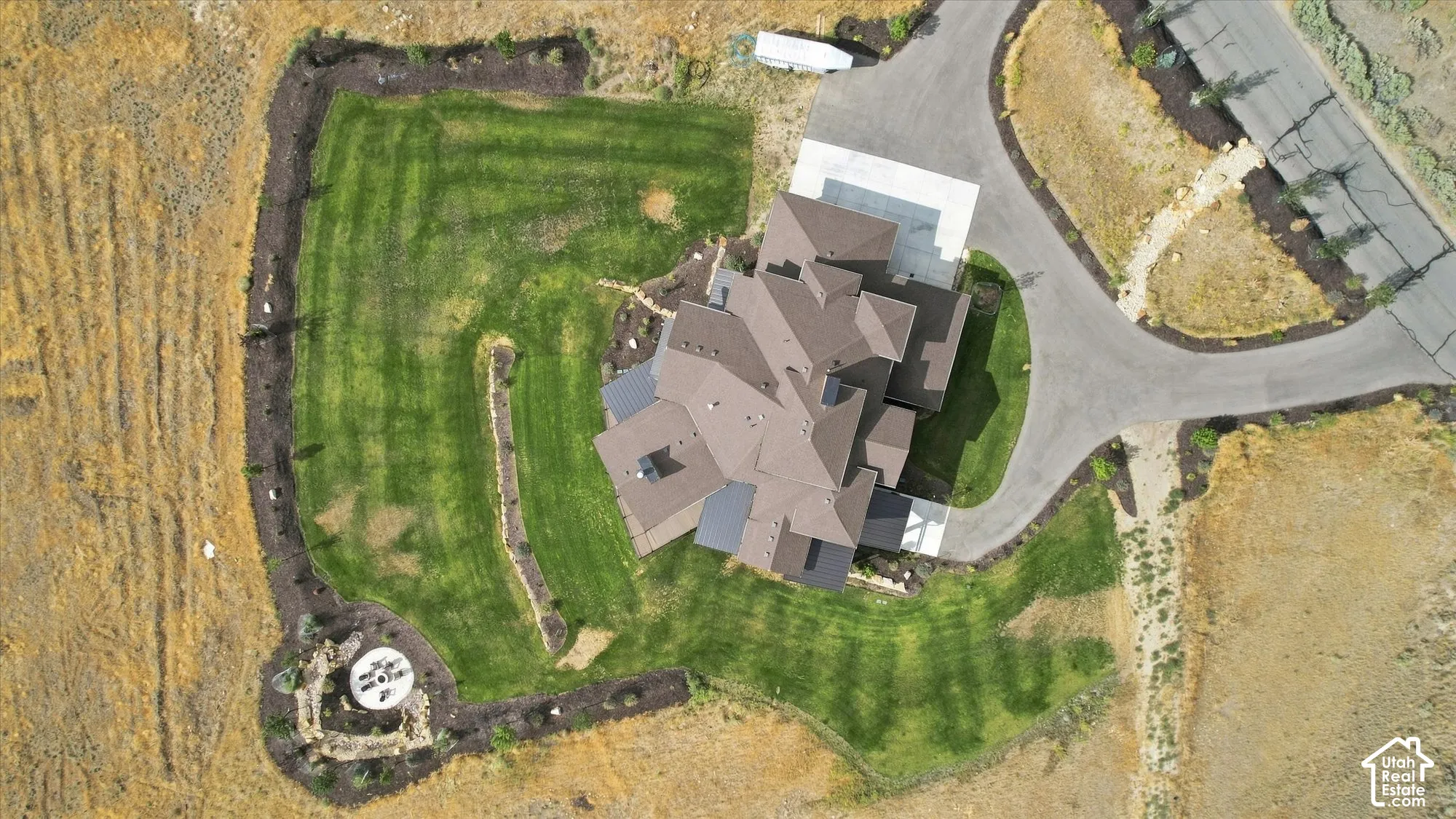 Expansive property featuring a multi-level roofline, well-maintained lawn, extensive landscaping, paved driveway, and dedicated parking pad