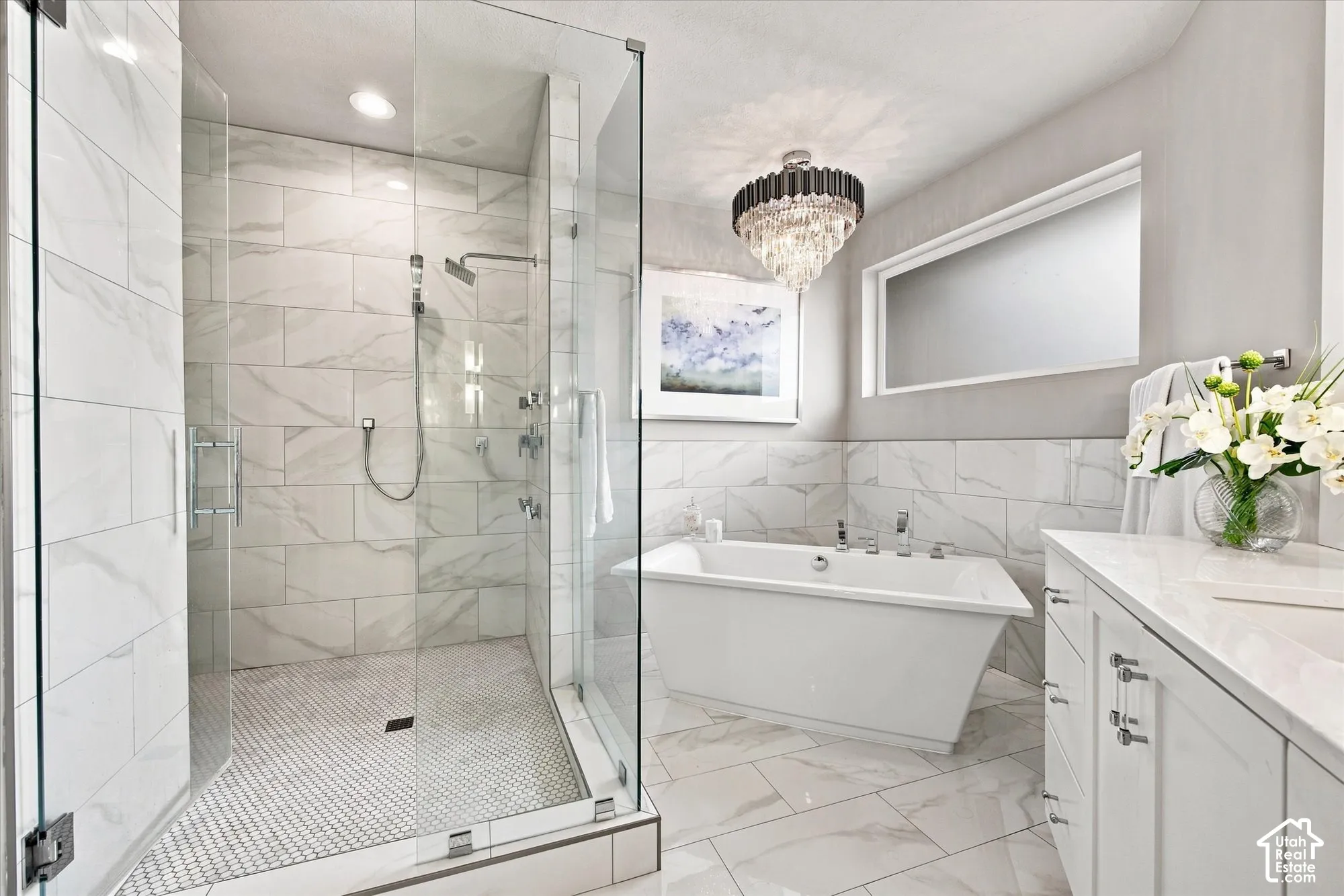 Primary En-suite bathroom featuring a freestanding tub, glass-enclosed shower with multiple showerheads, marble-patterned tile, and a vanity with an integrated sink