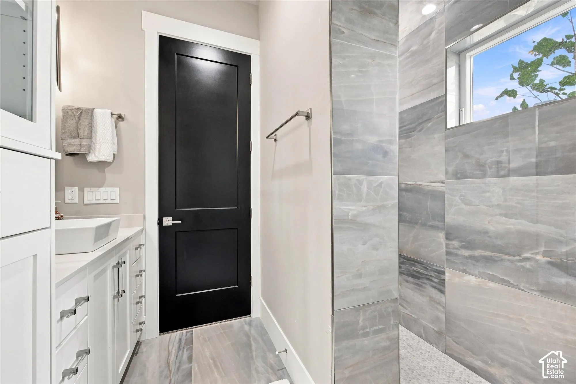 White shaker-style cabinetry with chrome hardware, a rectangular vessel sink, and an accent black door