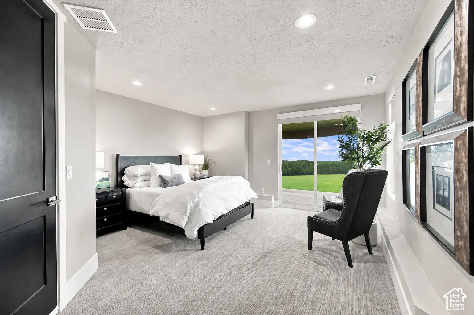 Recessed ceiling lighting, light gray wall finishes, carpeted flooring, sliding glass door, and a verdant outdoor landscape
