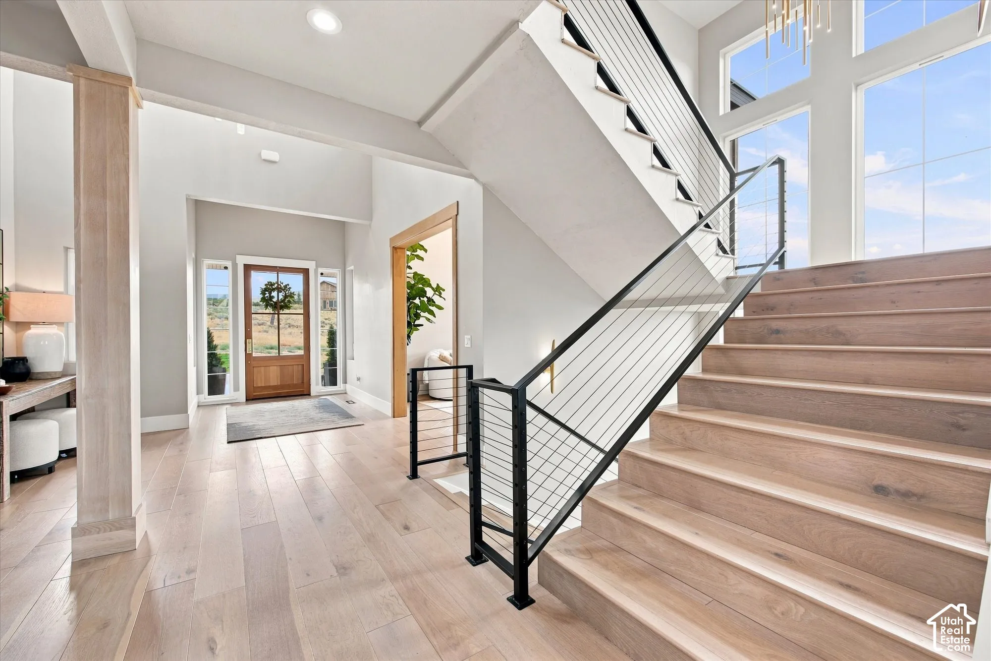 Entryway featuring wood-finish flooring, a solid wood entry door with sidelights, and a modern staircase with cable railing