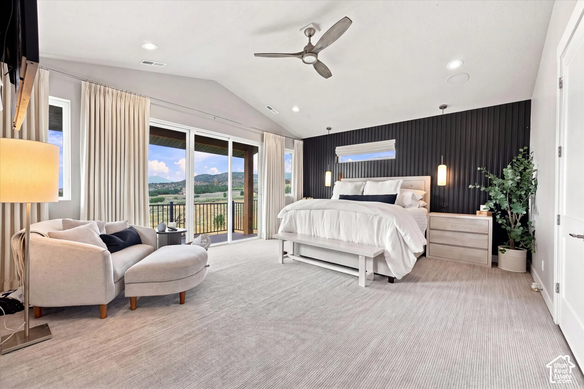 Primary Suite. Vaulted ceiling, ceiling fan, expansive glass sliding doors, private balcony with metal railing, and textured accent wall