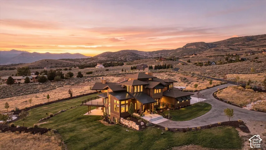 Multi-level architectural design featuring expansive windows, an outdoor deck, a lower-level patio, and a paved driveway