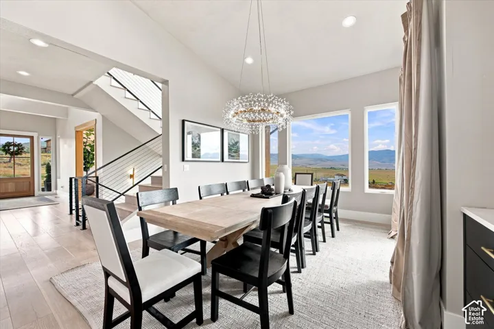 Vaulted ceilings, wood-finish flooring, a modern chandelier, a contemporary staircase with metal railings, and multiple windows
