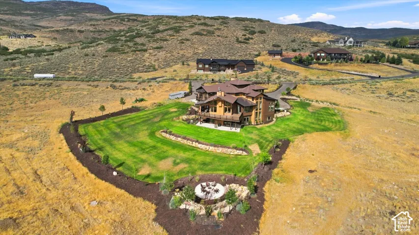 Expansive property featuring a multi-story residence with multiple balconies, a manicured lawn, and a stone fire pit area