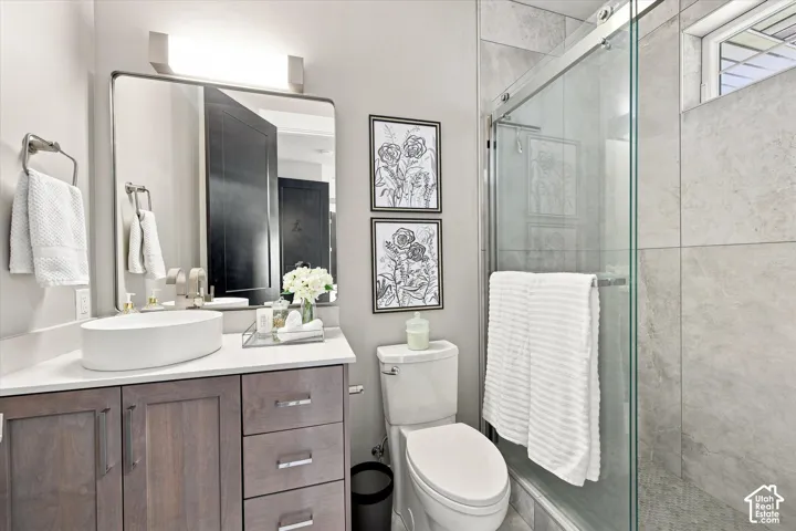 Vanity with wood-finish cabinetry, white countertop, and vessel sink