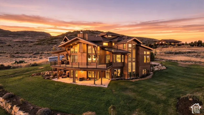 Multi-level wood-clad exterior with a prominent deck, expansive windows, and a lower-level patio