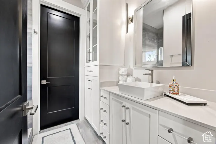 White vanity with a rectangular vessel sink, brushed nickel faucet, and a wall-mounted mirror