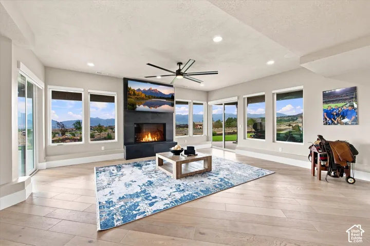 Spacious interior featuring wood-finish flooring, a contemporary fireplace with a dark stone surround, recessed lighting, and large windows