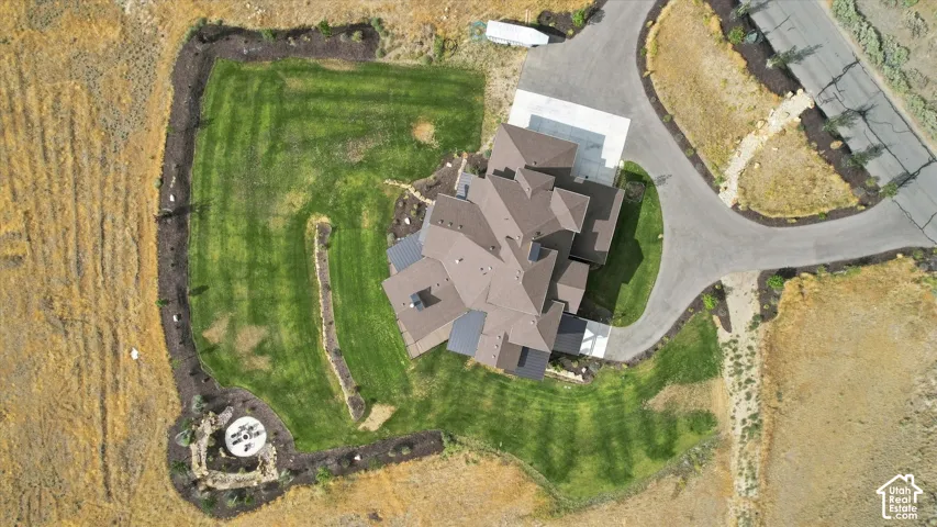 Expansive property featuring a multi-level roofline, well-maintained lawn, extensive landscaping, paved driveway, and dedicated parking pad
