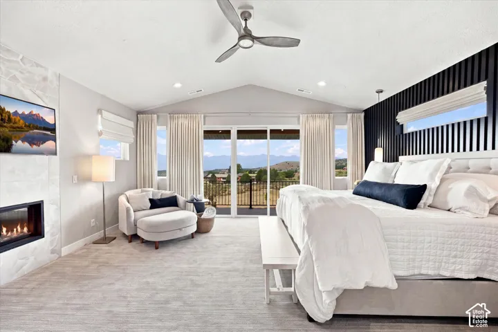 Primary Suite. Vaulted ceiling with recessed lighting, built-in fireplace with stone surround, large sliding glass doors, ceiling fan, and textured accent wall