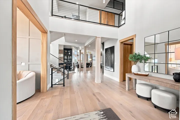 Grand entryway featuring light wood-finish flooring, a double-height ceiling, and a prominent open staircase with black metal railings