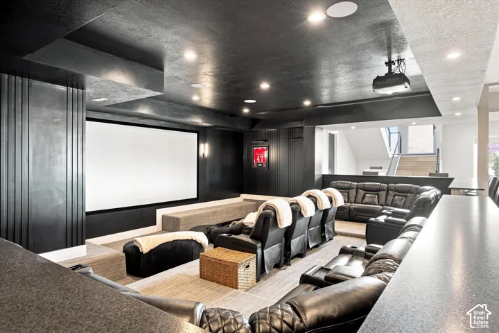 Integrated projector and screen, tiered seating, built-in counter, recessed lighting, and a partial staircase