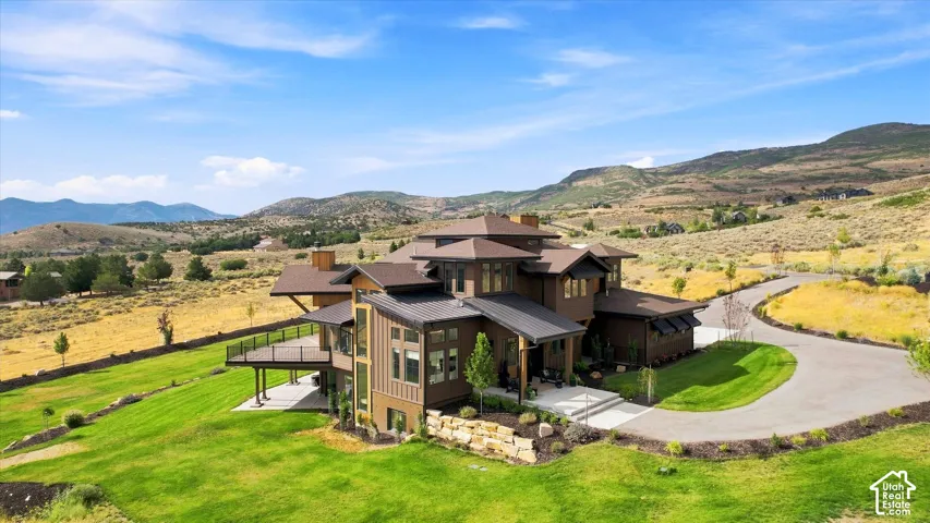 Multi-level residence featuring a tiered roofline, expansive outdoor deck, and a paved driveway