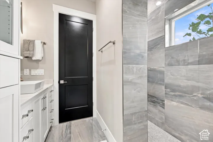 White shaker-style cabinetry with chrome hardware, a rectangular vessel sink, and an accent black door