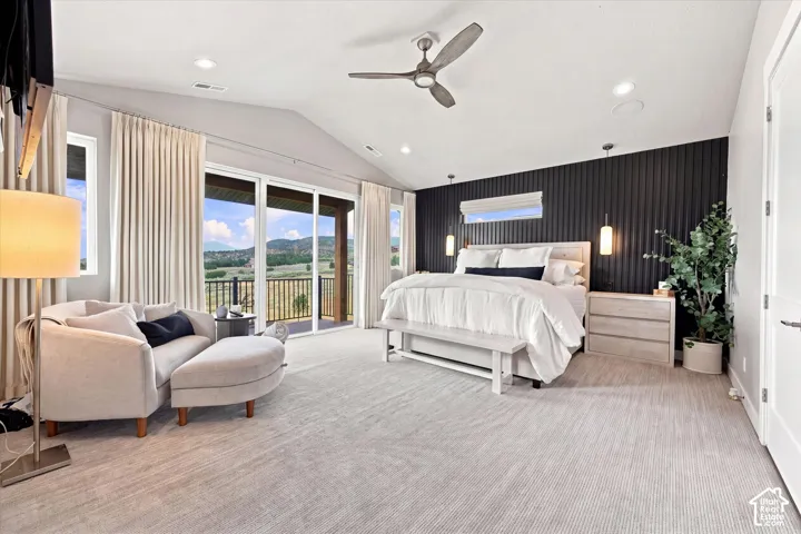 Primary Suite. Vaulted ceiling, ceiling fan, expansive glass sliding doors, private balcony with metal railing, and textured accent wall